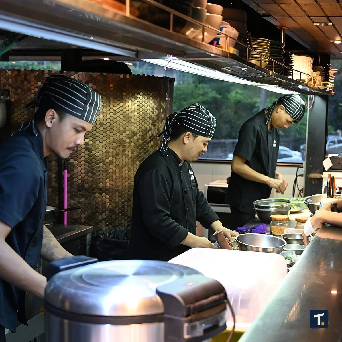 Cozinha profissional de restaurante com prato sendo preparado por cozinheiro.