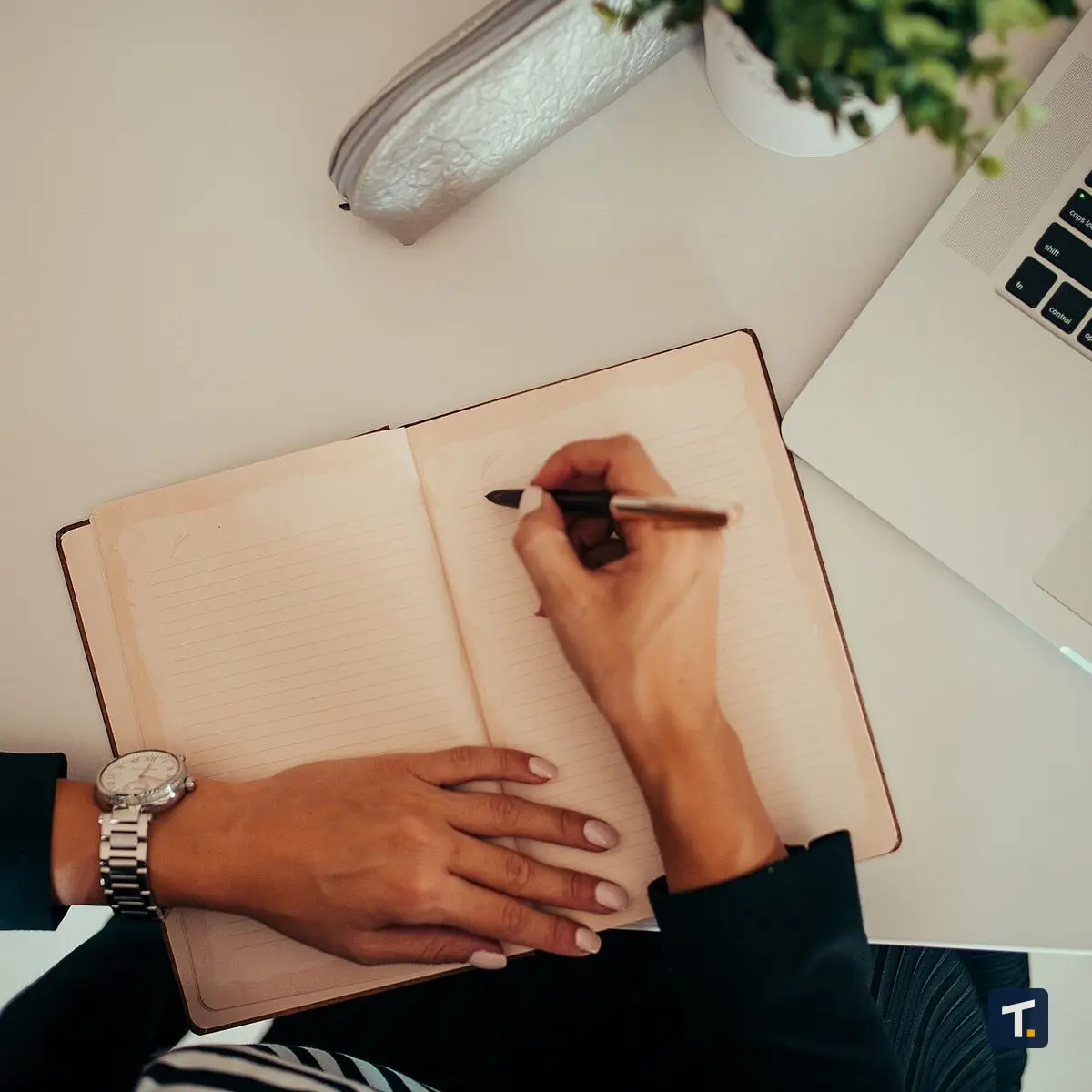 Mesa de escritório organizada com notebook, bloco de notas e caneta, representando o ambiente de trabalho administrativo.